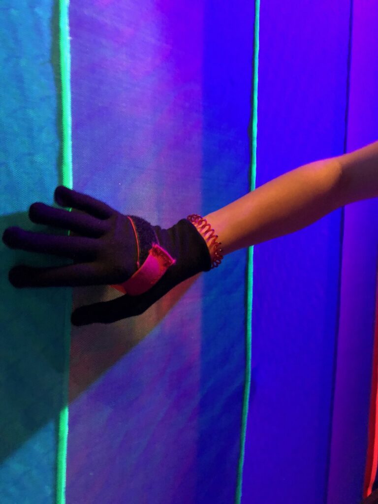 A hand in the special glove pressed against the glowing fabric wall