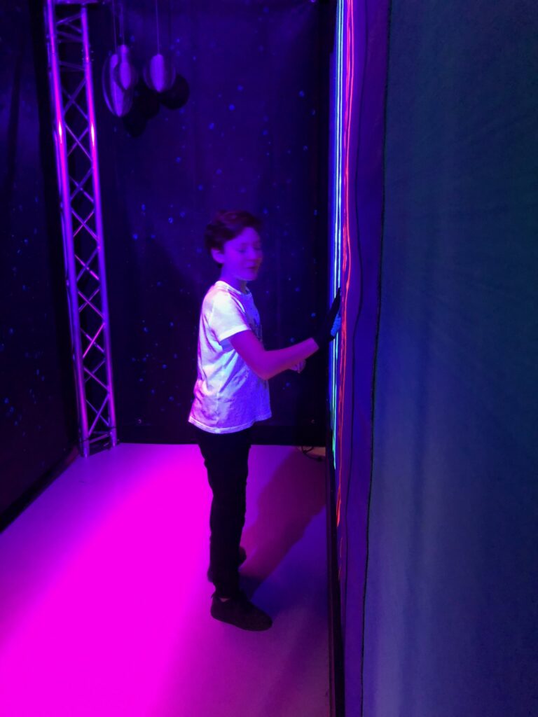 A young visitor touching the wall in the purple light